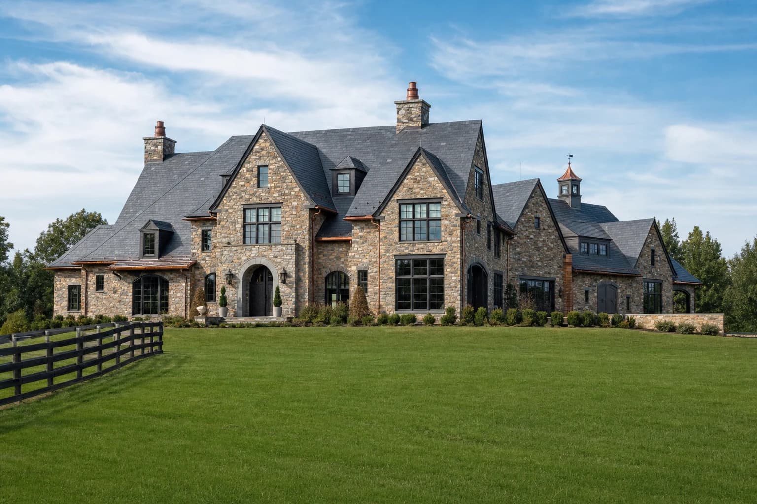 Luxury historic fieldstone custom estate sitting on sprawling green pastures in Middleburg, Virginia, with a slate roof and copper gutters