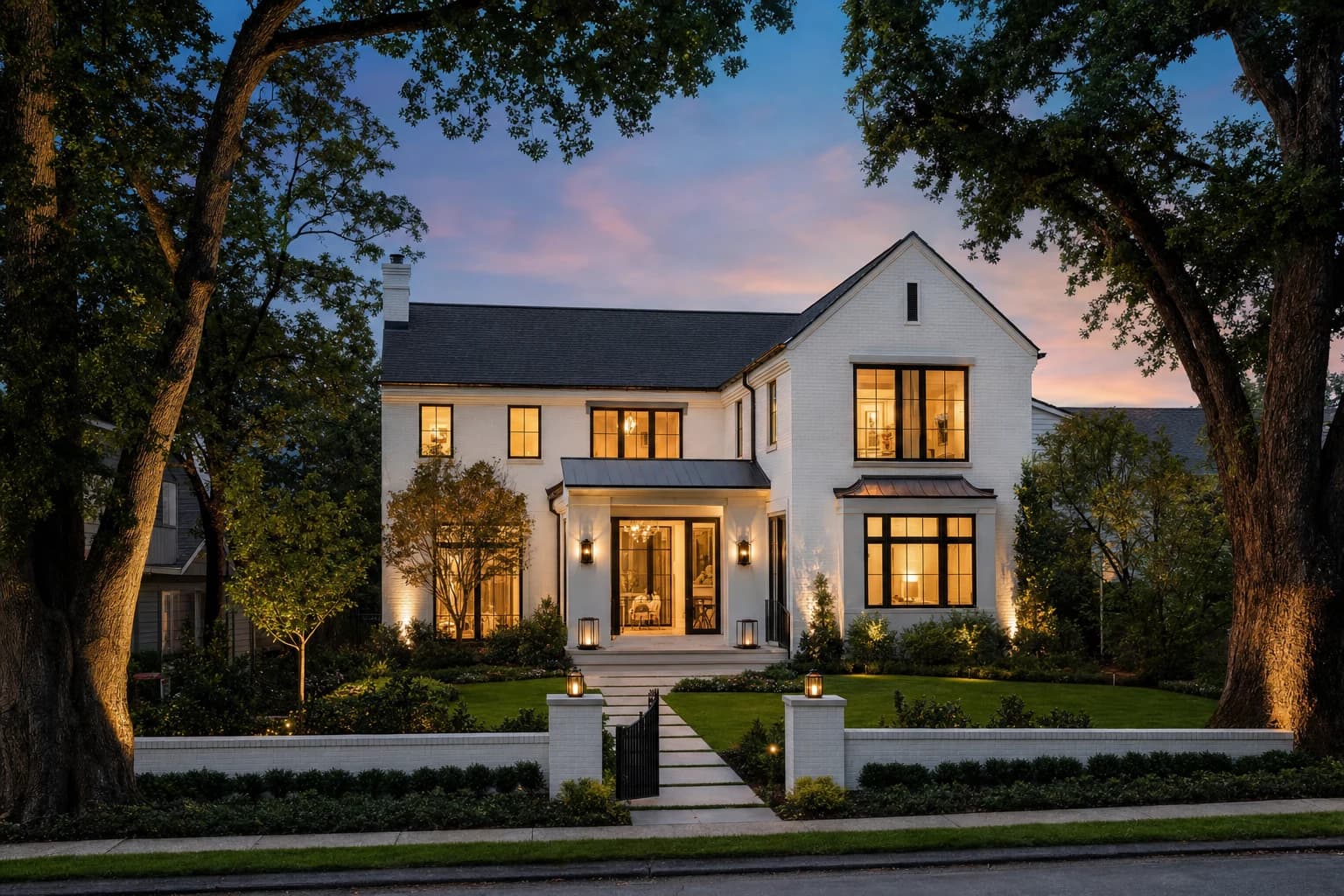 A breathtaking twilight shot of a modern transitional luxury custom home on a tight, manicured infill lot in downtown Vienna, Virginia, surrounded by massive legacy oak trees